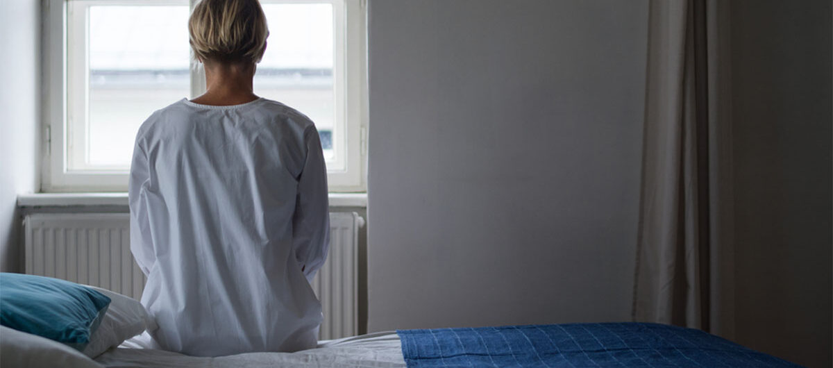 rearviewofwomanpatientsittingonbedinhospital